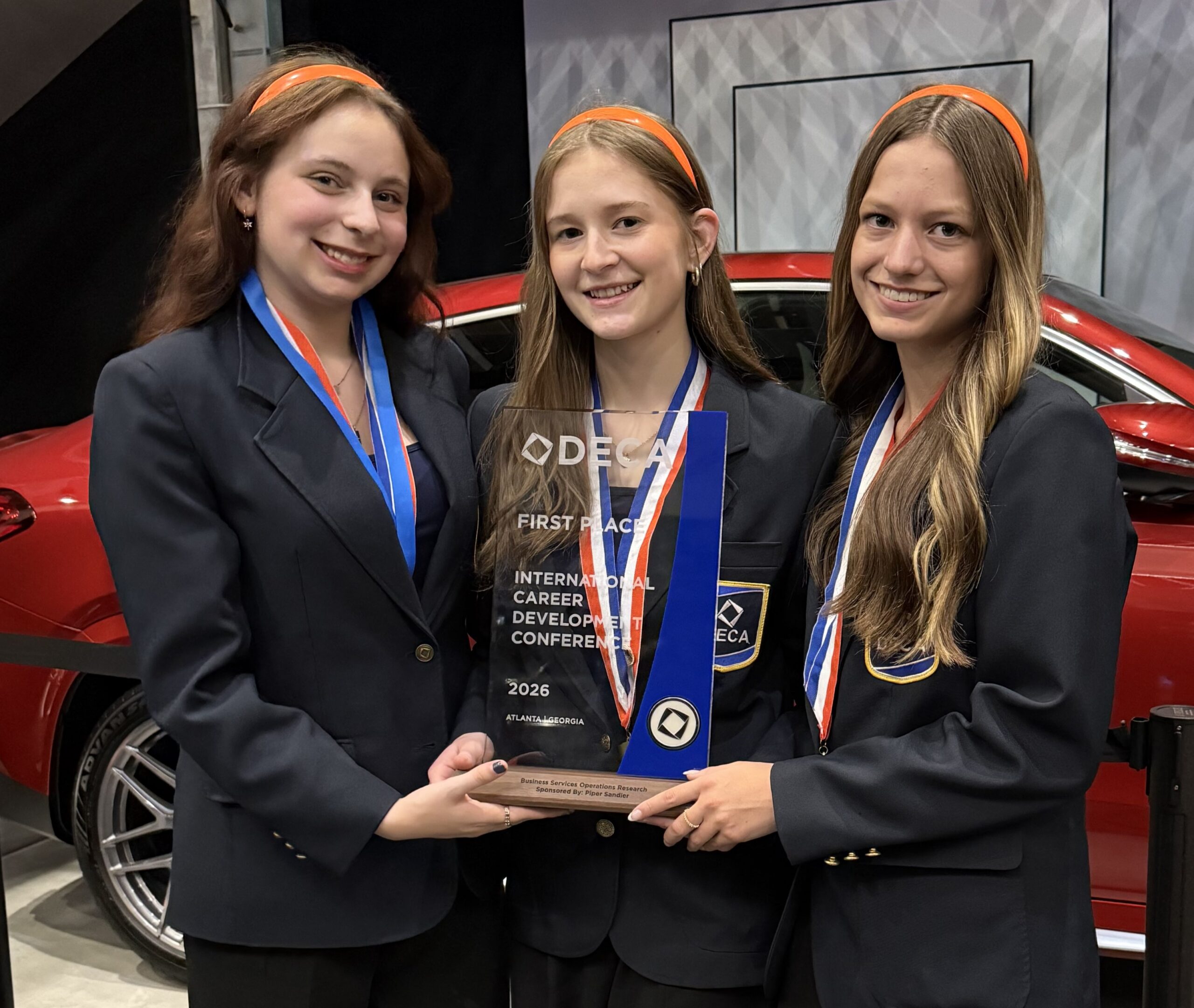 the three 2026 DECA Winners holding trophy